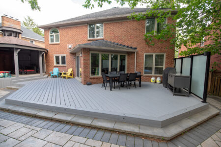 Wide view of a completed composite backyard deck with black railings