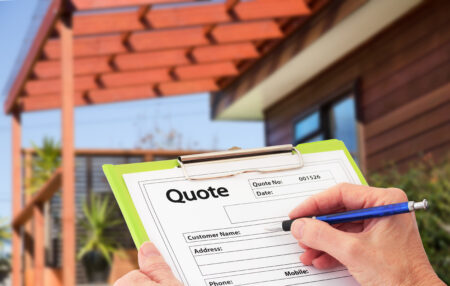 A person holding a clipboard with a Toronto Deck Free Estimate form, writing with a pen. The background features a modern wooden house with a pergola and lush greenery. The form includes fields for customer name, address, phone, and mobile.