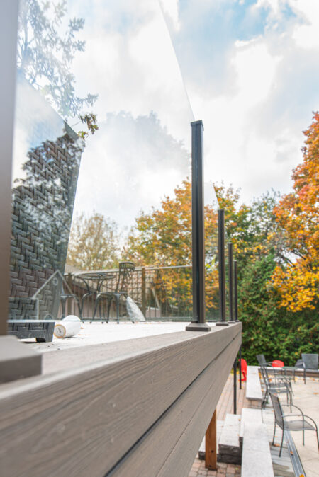 Glass railing along an elevated deck overlooking the backyard.