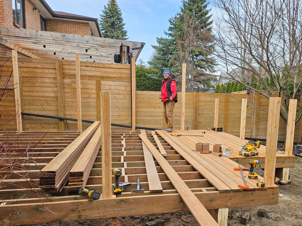 Construction worker building a wooden backyard deck.