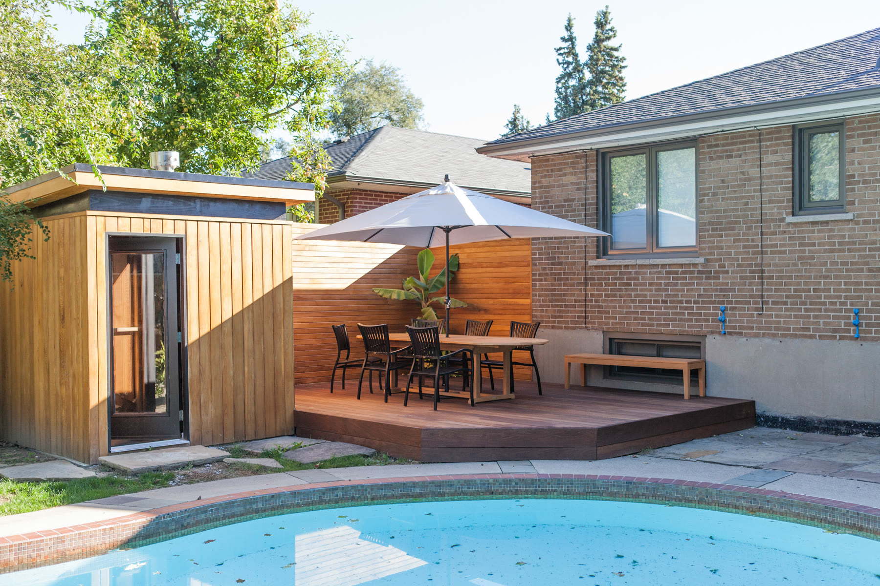 Completed backyard pool deck with wood-look decking and black aluminum railings