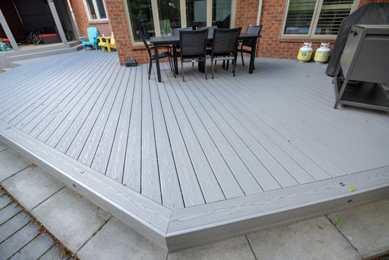 Diagonal grey composite deck boards and picture-frame border beside the outdoor dining area
