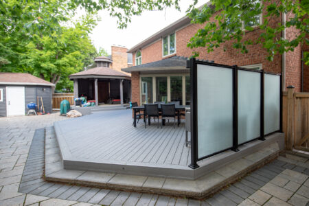 Angled view across the Fiberon Cottage deck toward the gazebo and black-framed frosted glass privacy screen